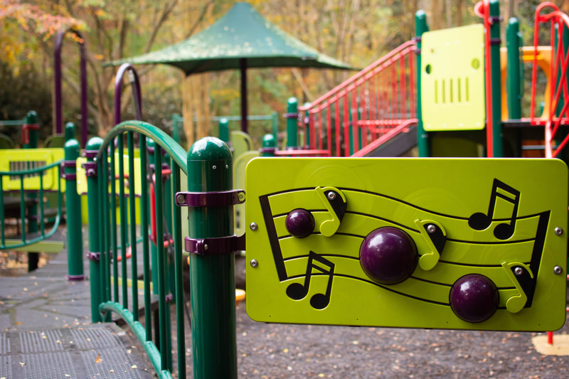 Interactive musical play wall in the foreground, wheelchair accessible play structure in background at Kids Together Playground in Cary, North Carolina